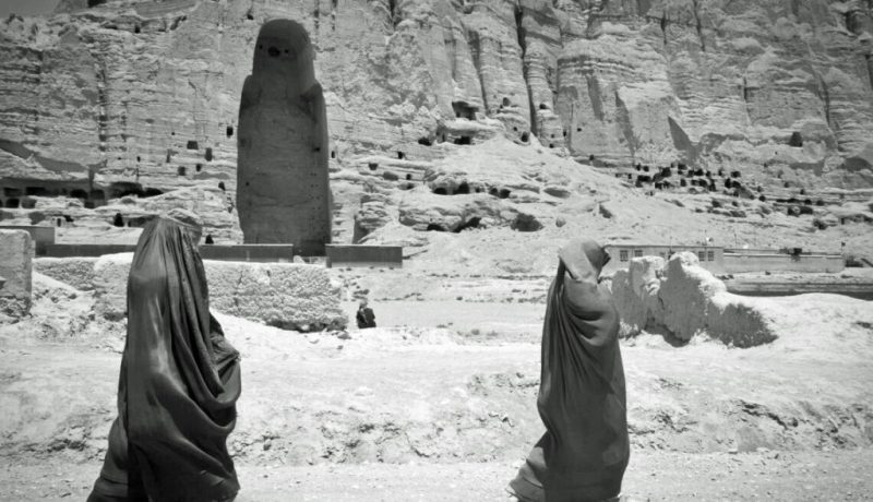 Due donne passano davanti all'enorme cavità dove si trovava uno degli antichi Buddha di Bamiyan. Foto del sergente Ken Scar, 2012. Fonte: flickr.com/photos/dvids/7408738172