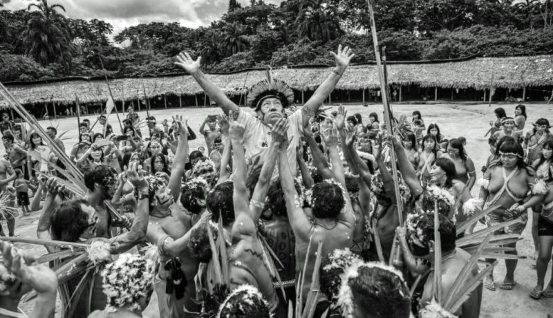 Davi Kopenawa Yanomami viene sollevato nel centro del villaggio Xihopi, Terra indigena Yanomami, nello Stato di Amazonas. Foto di Christian Braga/ISA. Fonte: https://www.socioambiental.org